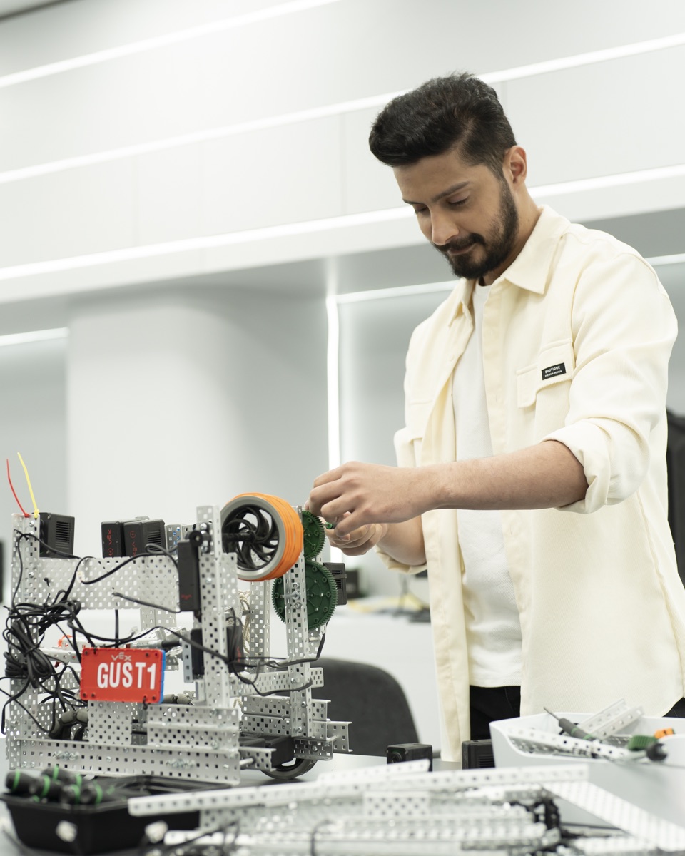 A student working on a robotics platform in a GUST laboratory